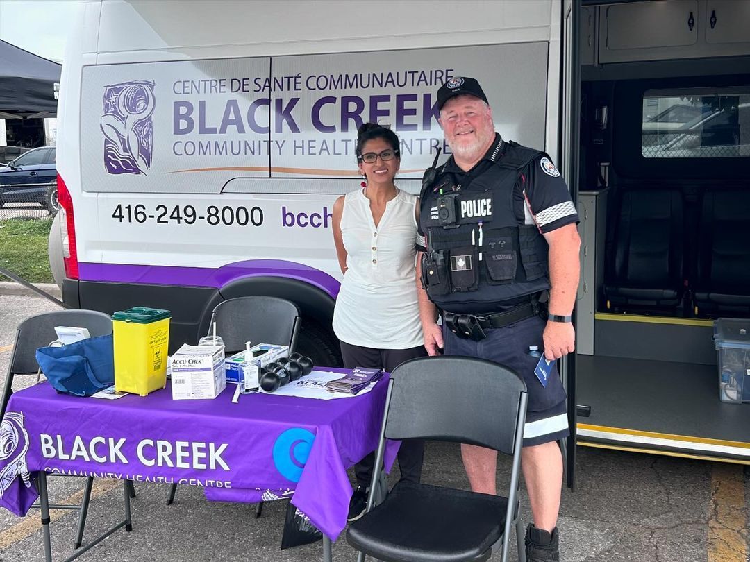 A man and a woman are posing for a picture in front of a black creek community health center.