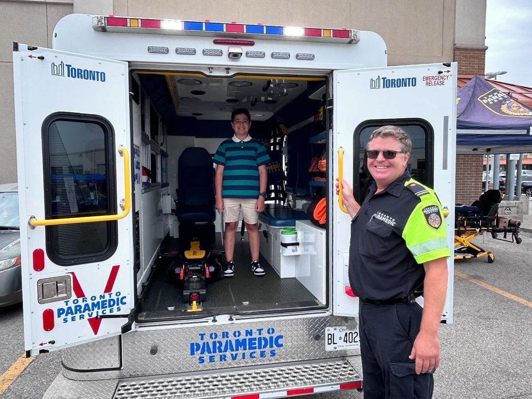 A man is standing in front of an ambulance with the door open.