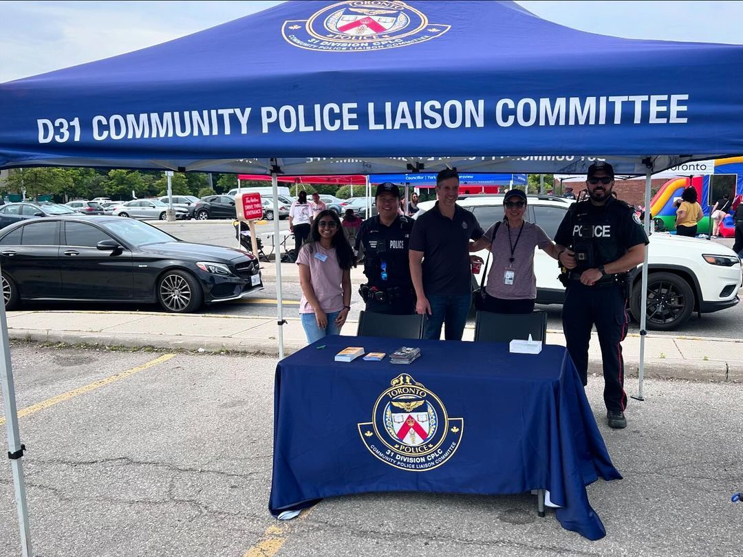 A group of people standing around a table under a blue tent.