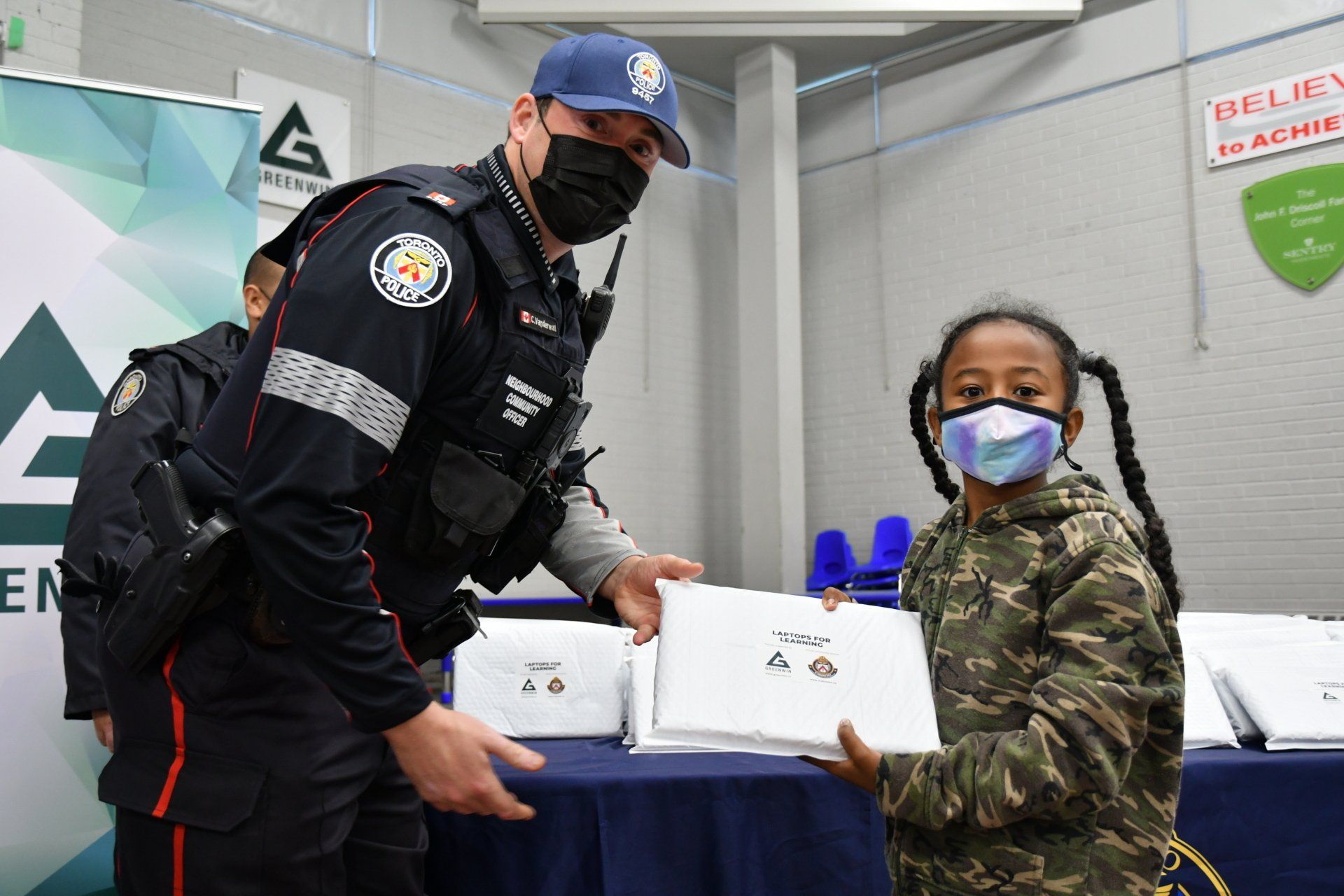 Officer giving laptop to student