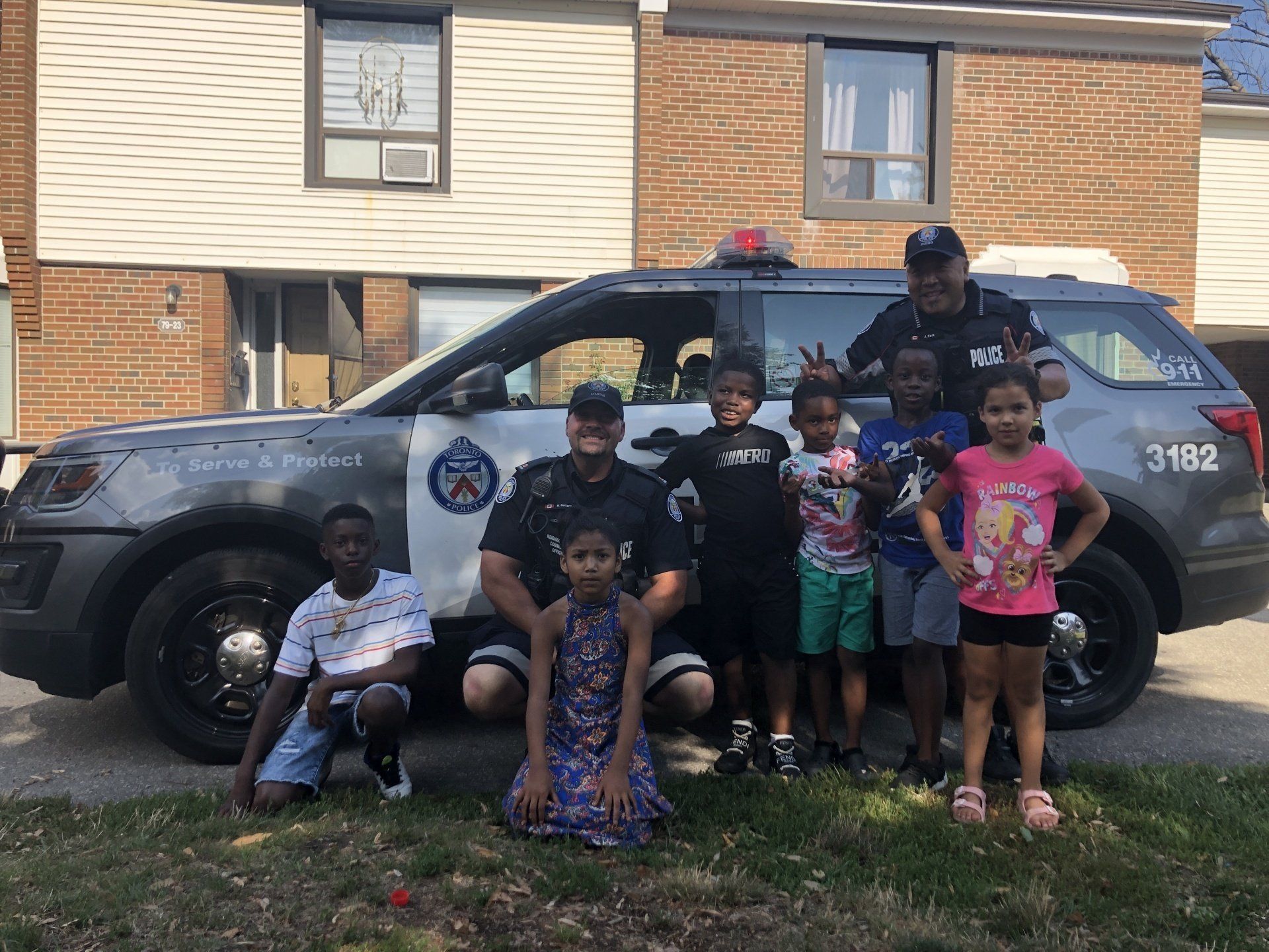 Photo of officers and children in front of police vehicle