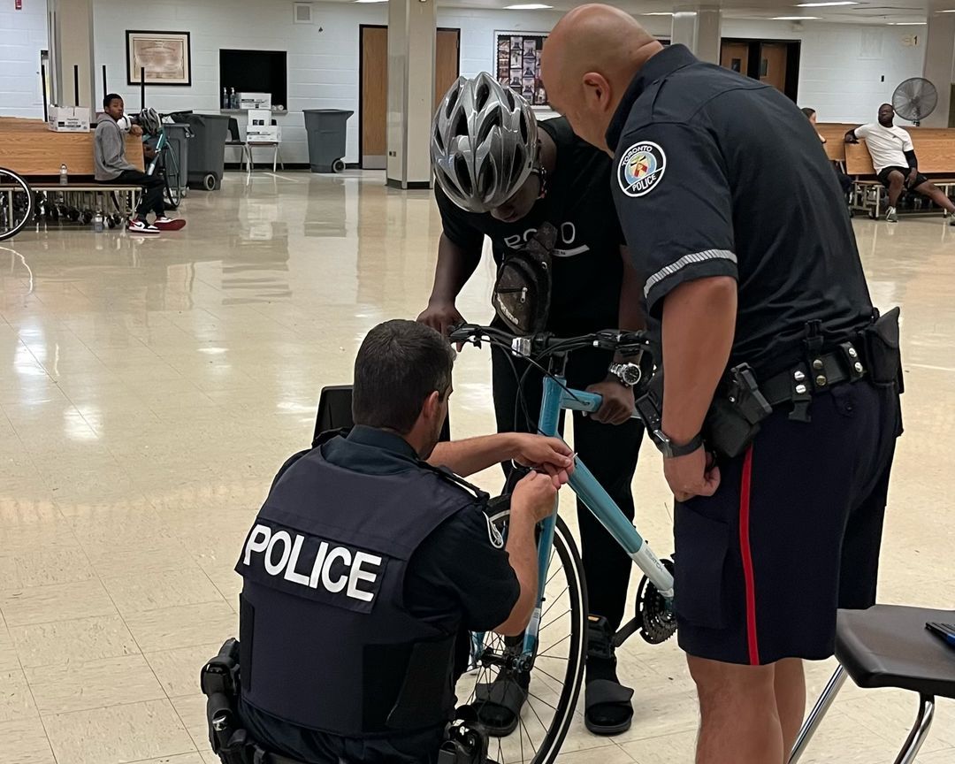 Two police officers are working on a bicycle in a hallway.