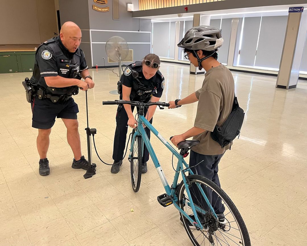 Two police officers are helping a man fix his bike