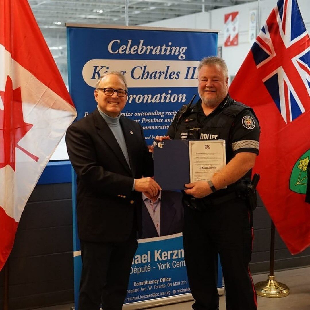two men shaking hands in front of a banner that says celebrating King Charles III