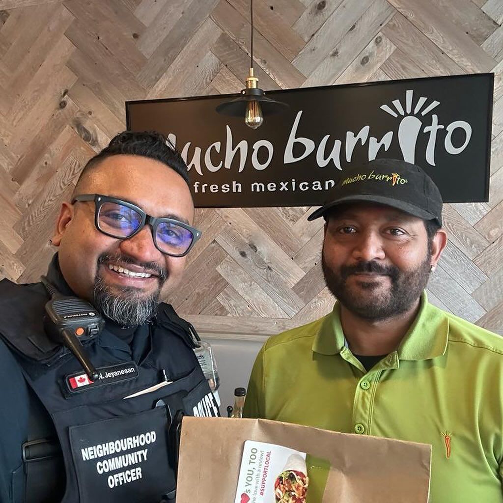 two men are posing for a picture in front of a sign that says nacho burrito