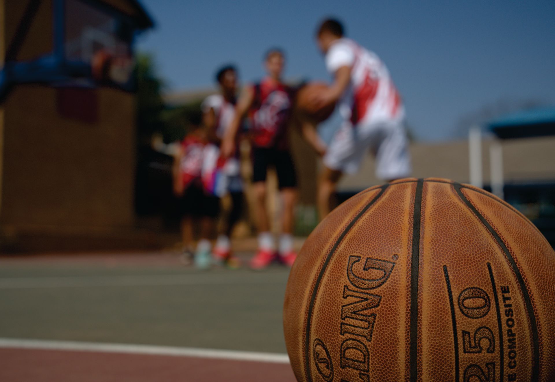 Basketball on court with players blurred in background.