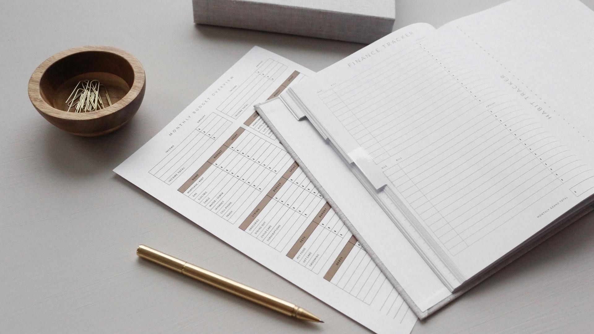 A pencil is sitting on top of a piece of paper next to a bowl of paper clips.