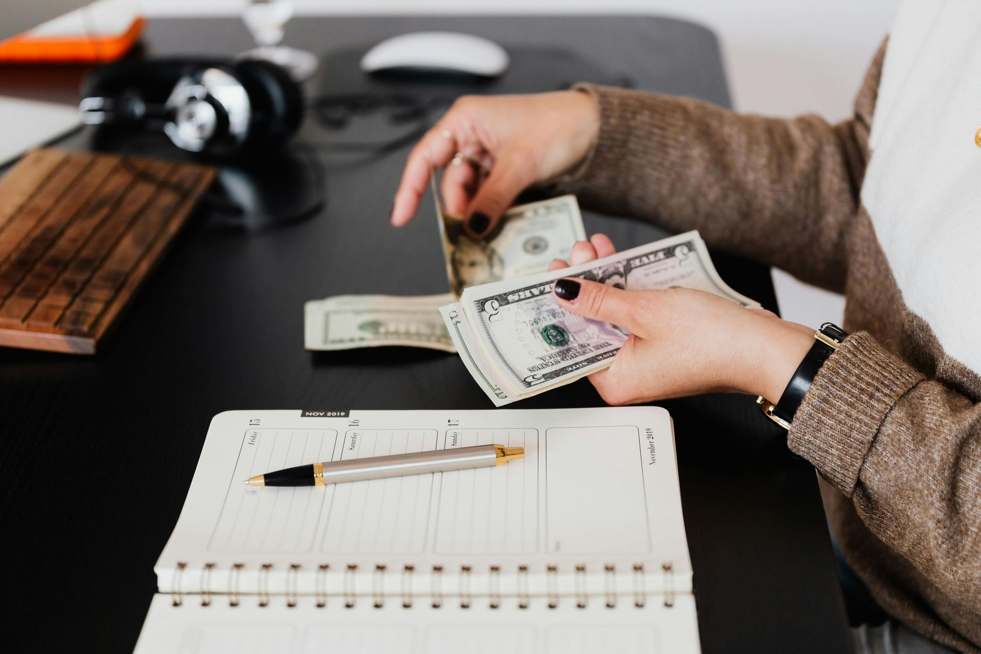 A woman is sitting at a desk counting money.