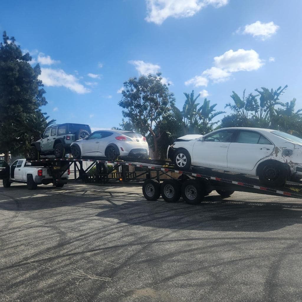 Two car carrier trailers loaded with vehicles parked under a blue sky.