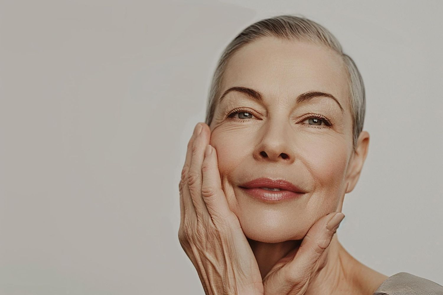 An older woman is smiling and touching her face with her hand.