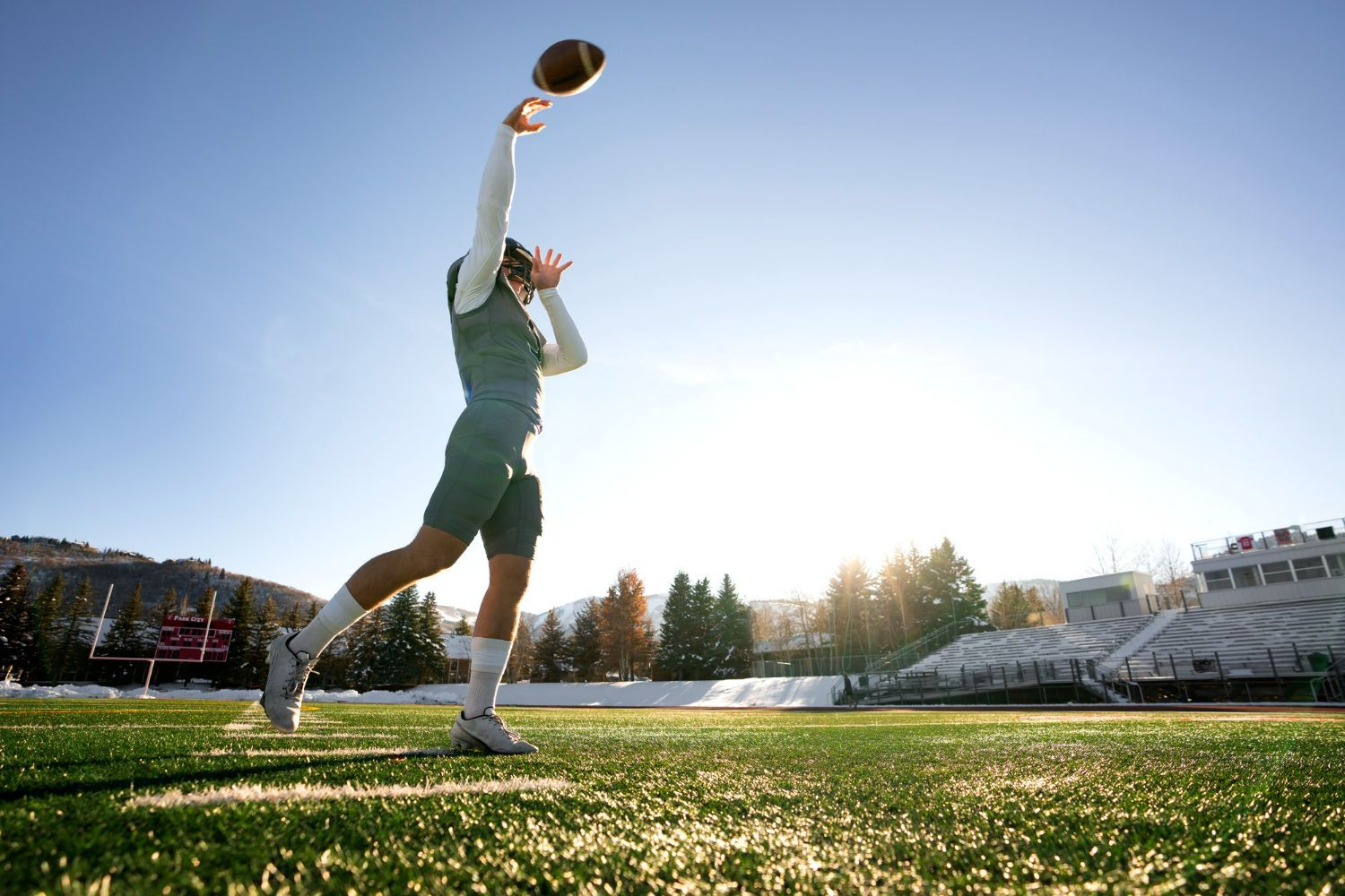 A man is throwing a football in the air on a field.