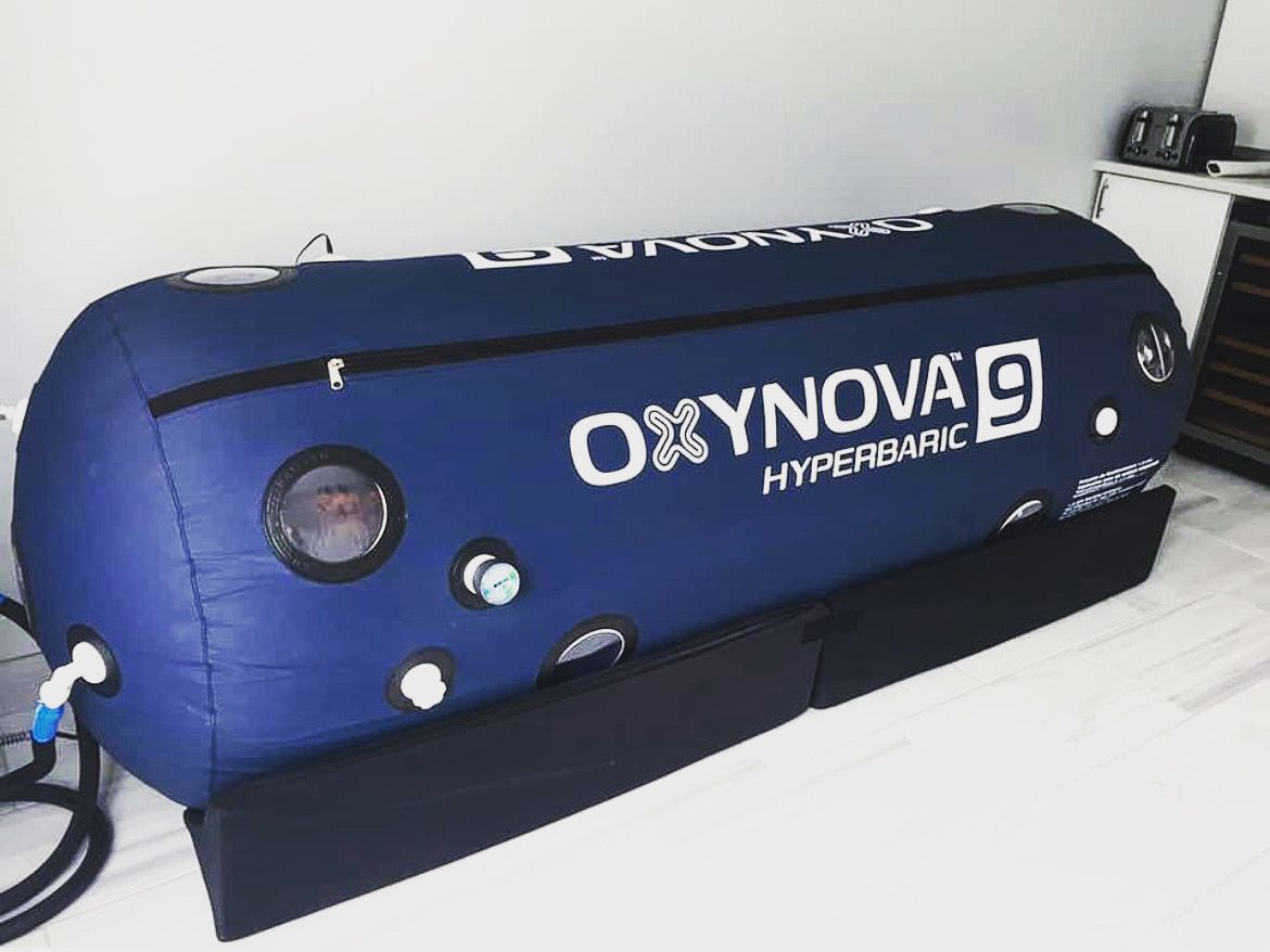 a blue oxynova hyperbaric chamber is sitting on a bed .