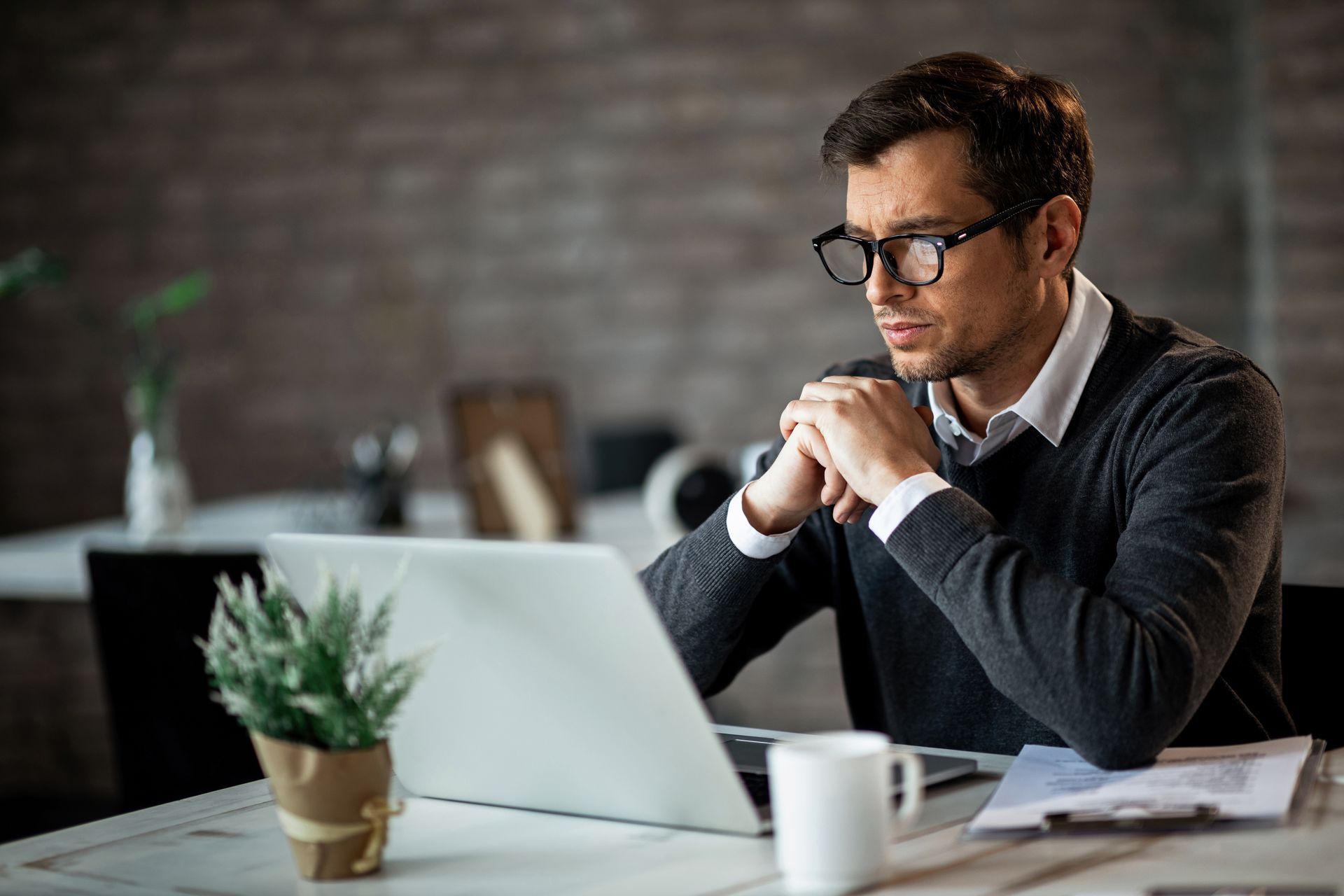 a man is sitting at a desk using a laptop computer .