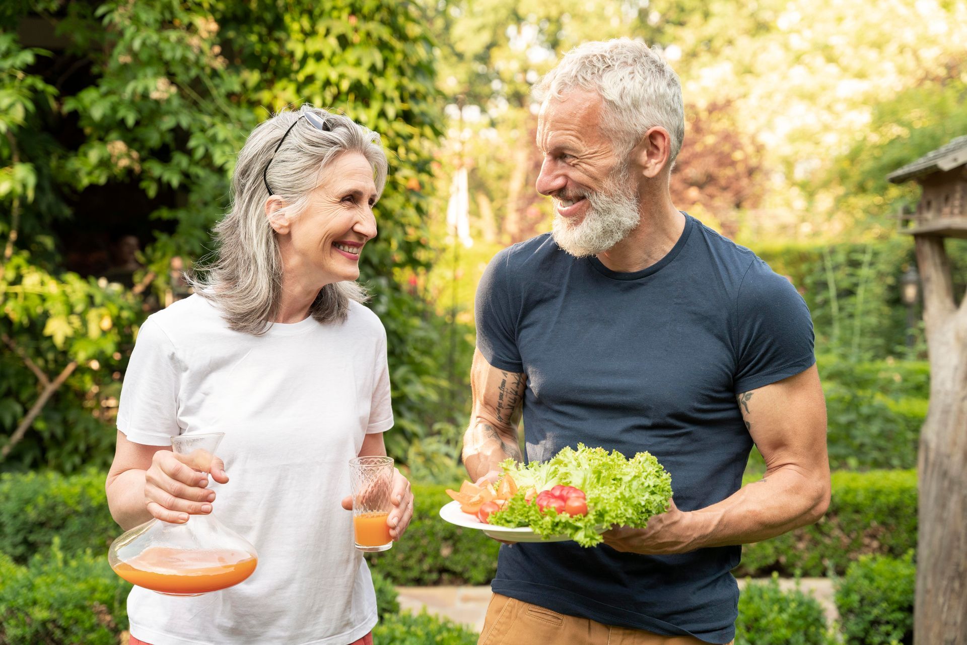 a man holding a plate of salad and a woman holding a glass of orange juice