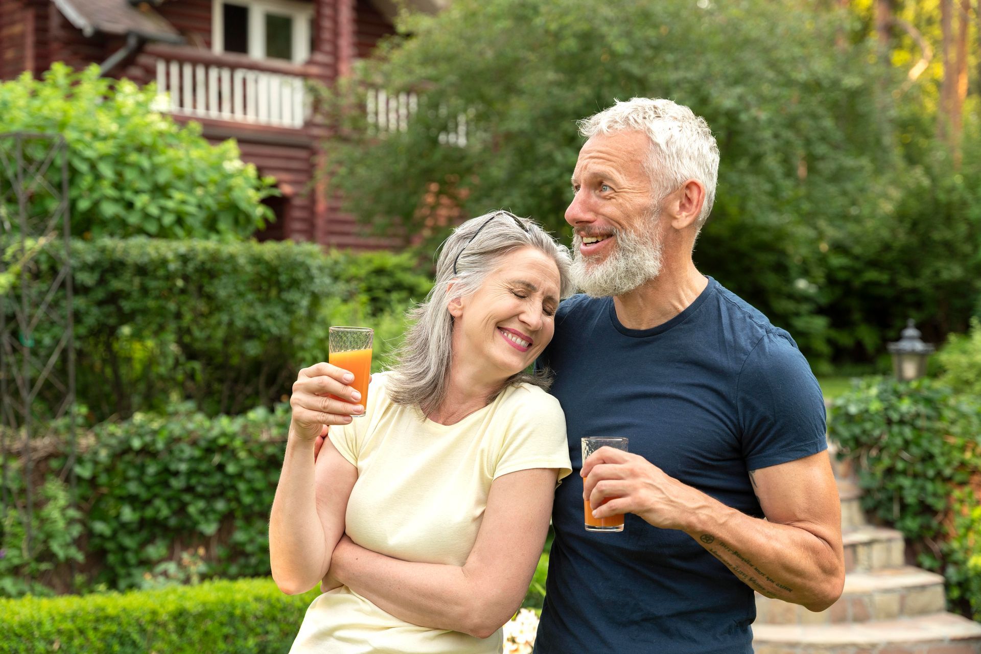 a man and a woman are standing next to each other holding glasses of orange juice .