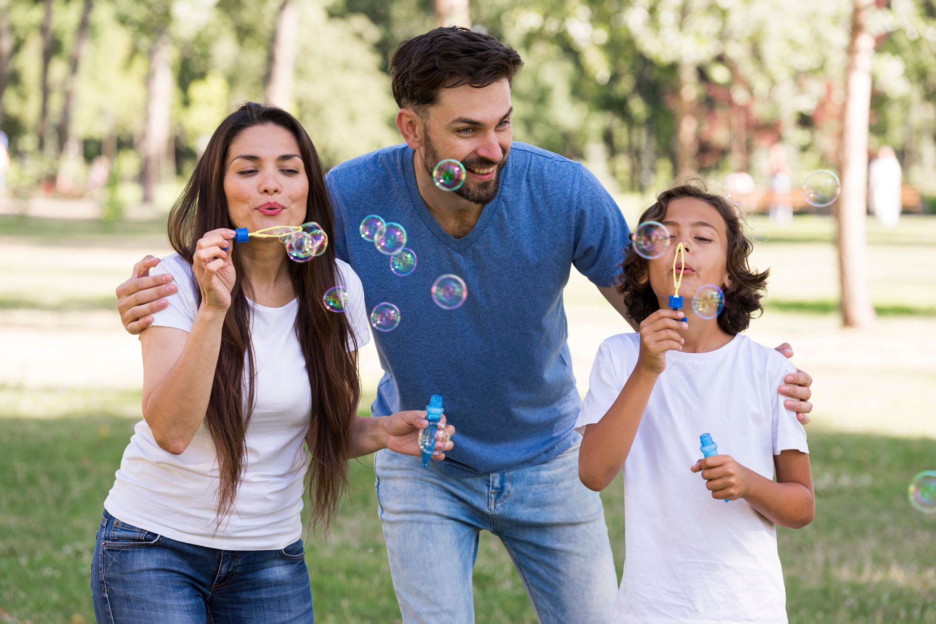 a family is blowing soap bubbles in a park .