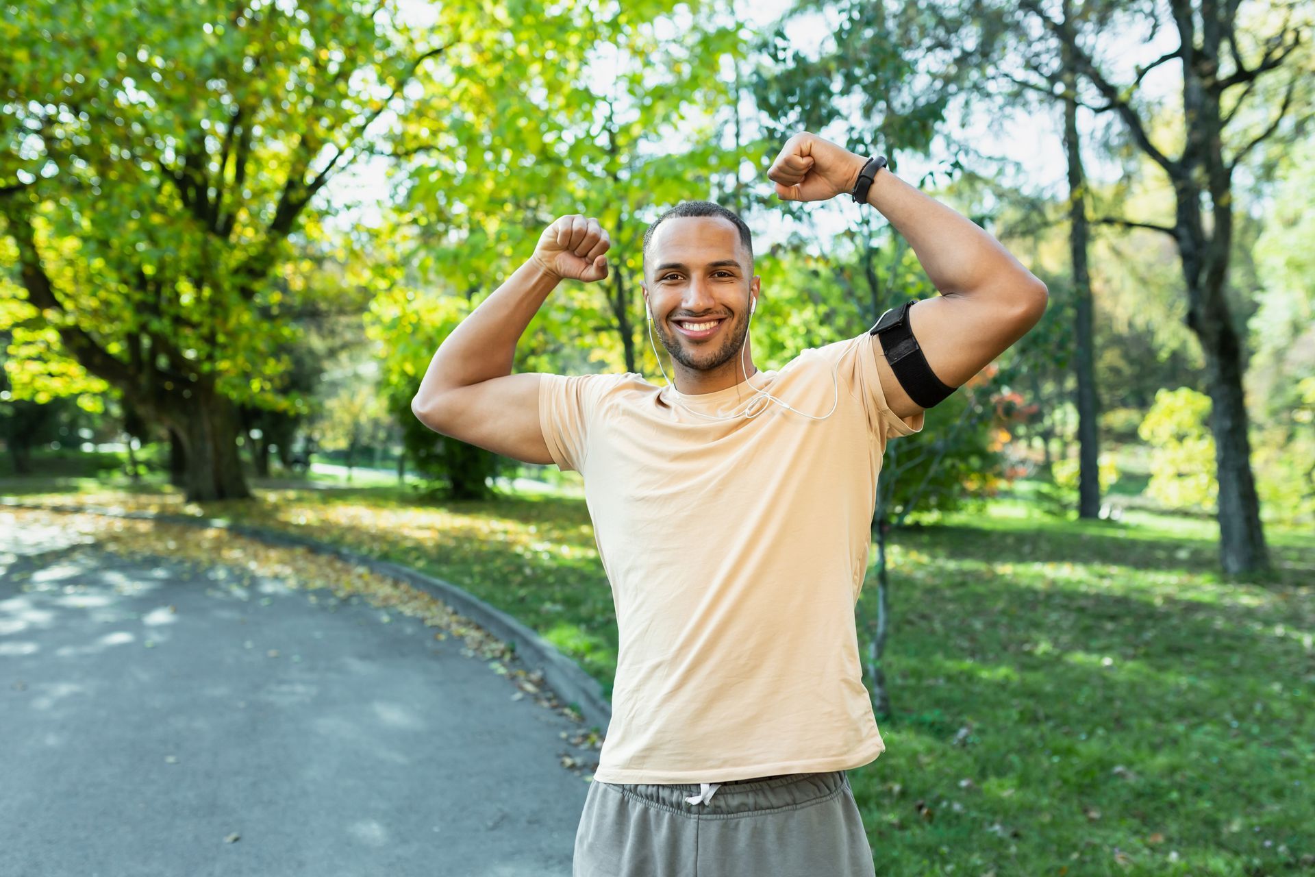 A man is flexing his muscles in a park.