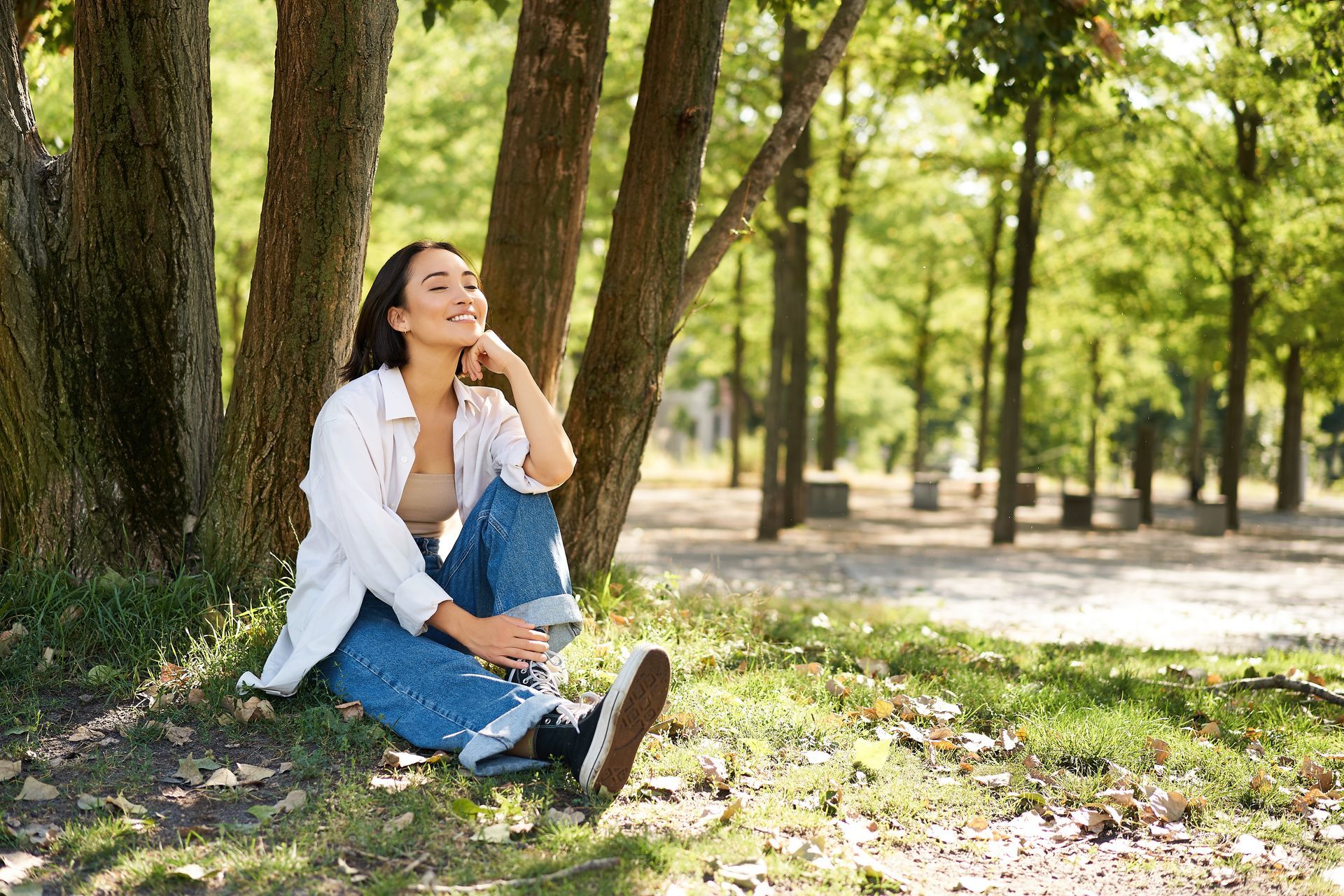 a woman is sitting under a tree in a park .