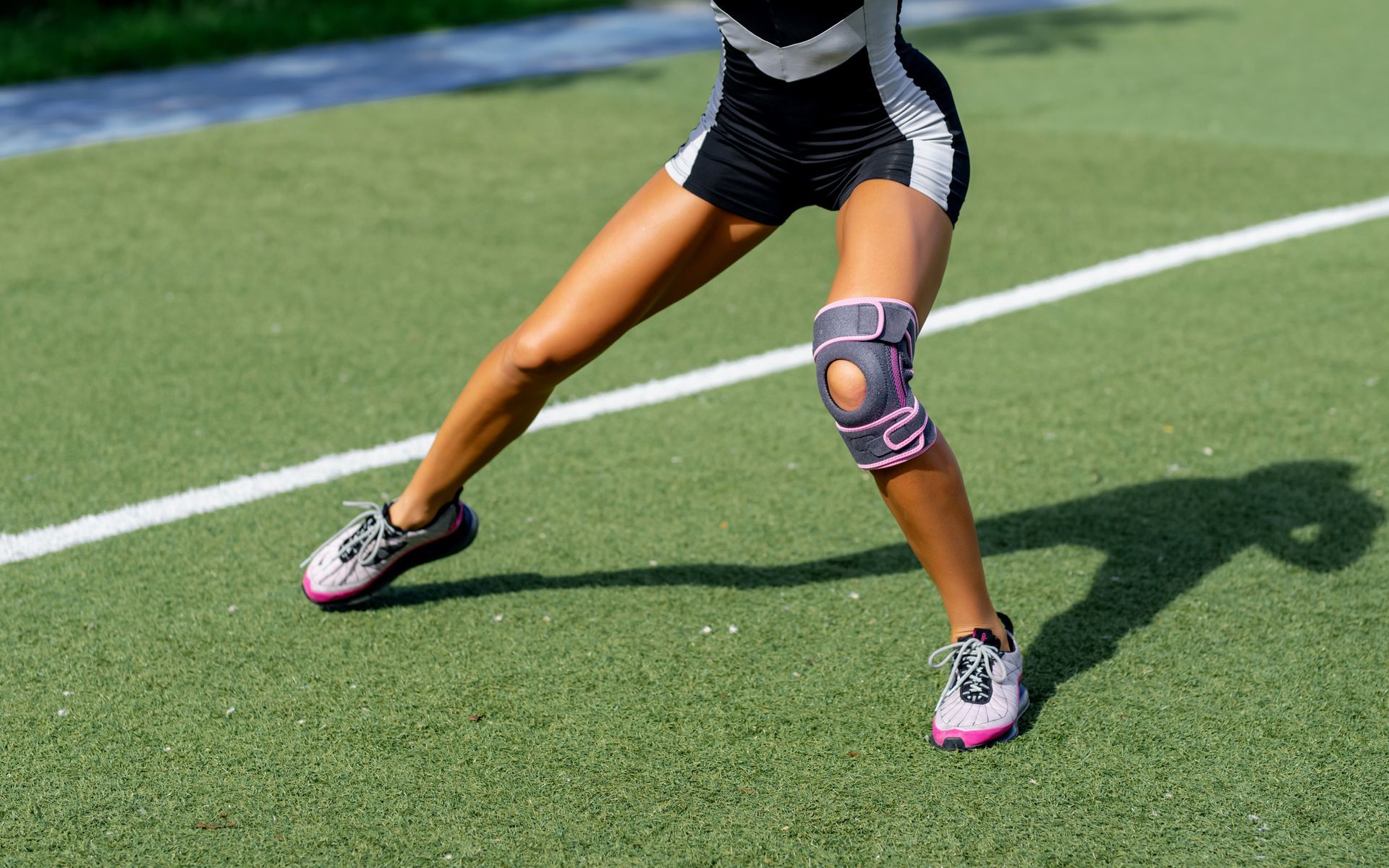 a woman wearing a pink knee brace on a soccer field