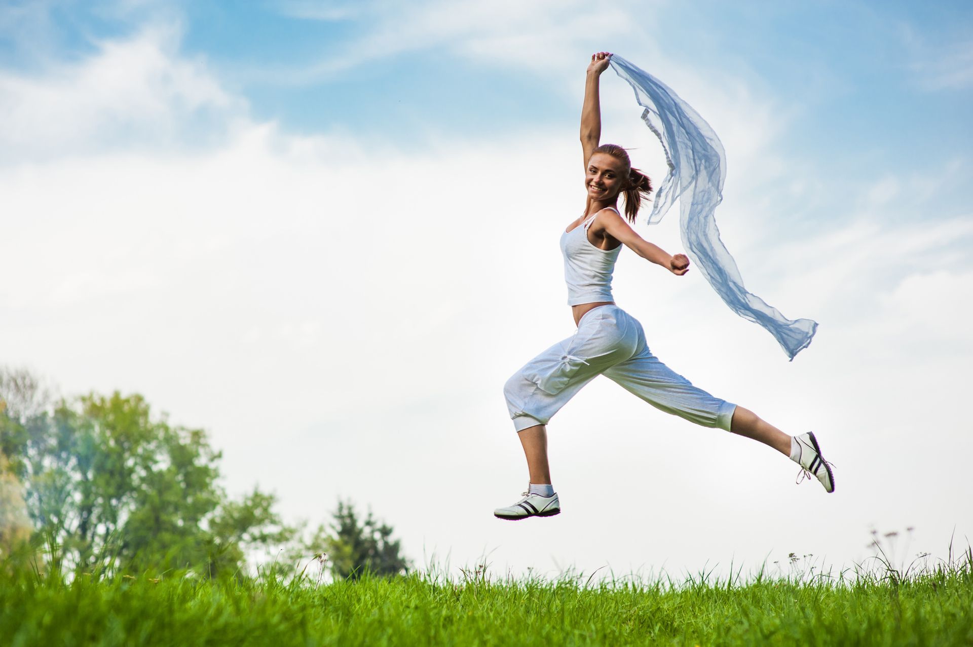 a woman is jumping in the air while holding a scarf .