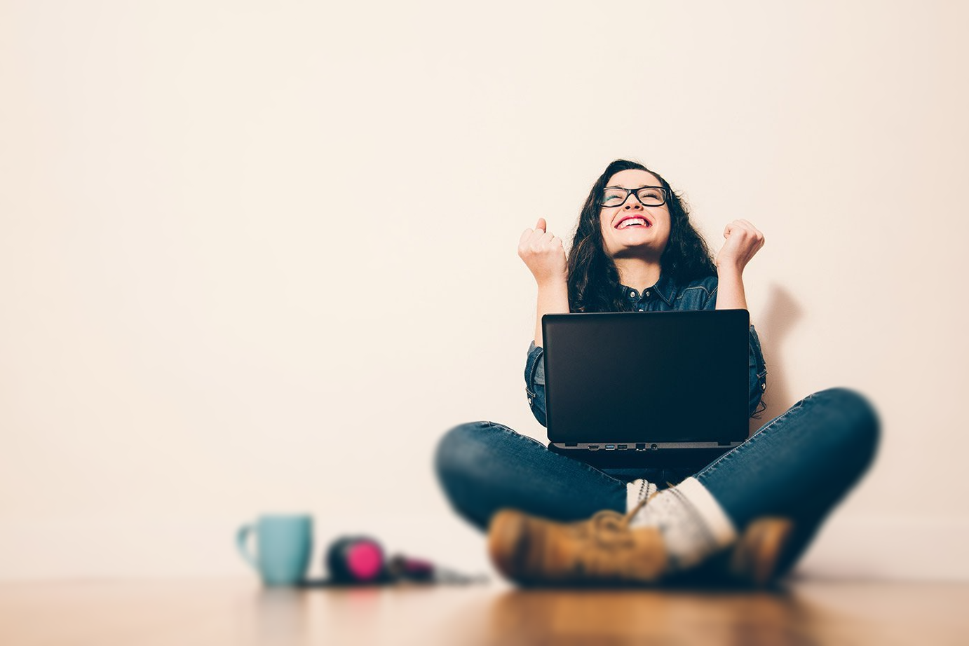 Uma mulher está sentada no chão usando um laptop.