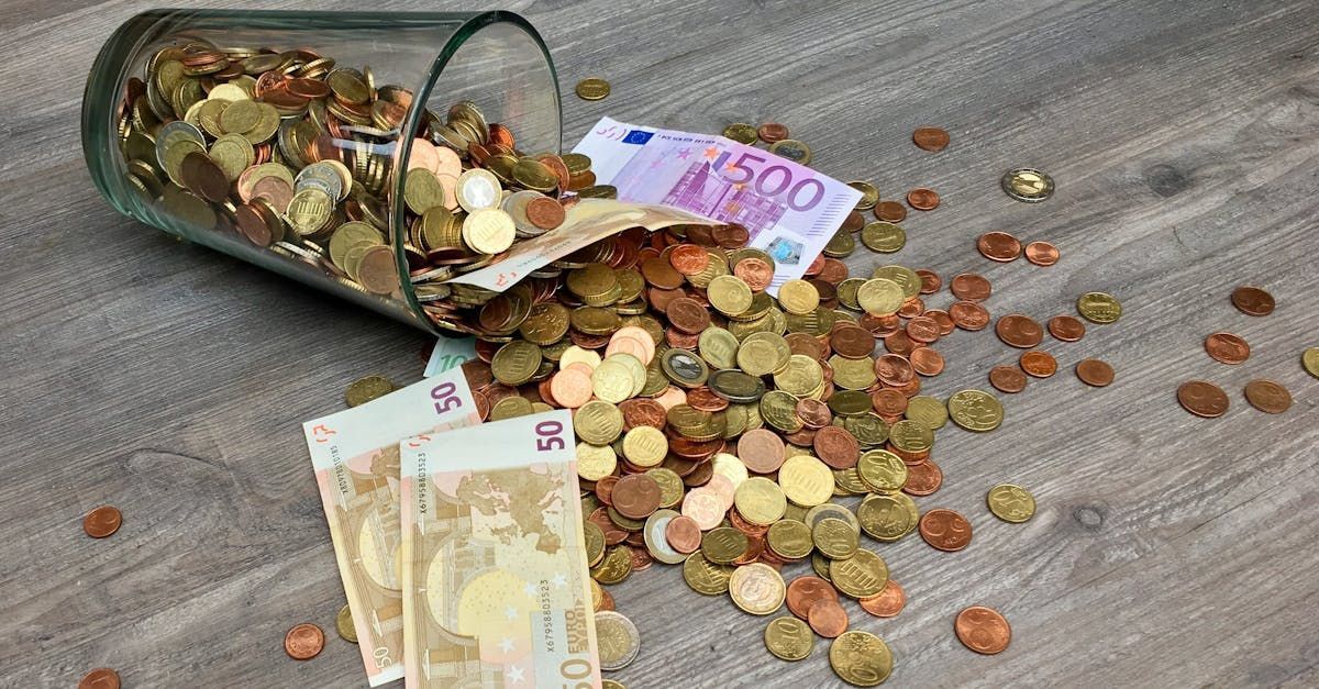 Um copo cheio de dinheiro e moedas está caindo sobre uma mesa de madeira.