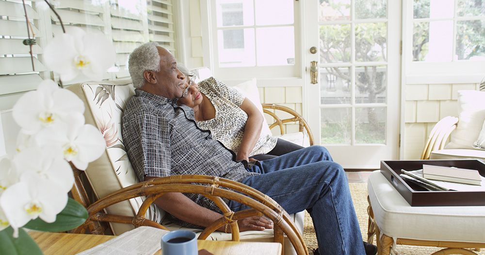 An elderly couple is sitting on a couch in a living room.