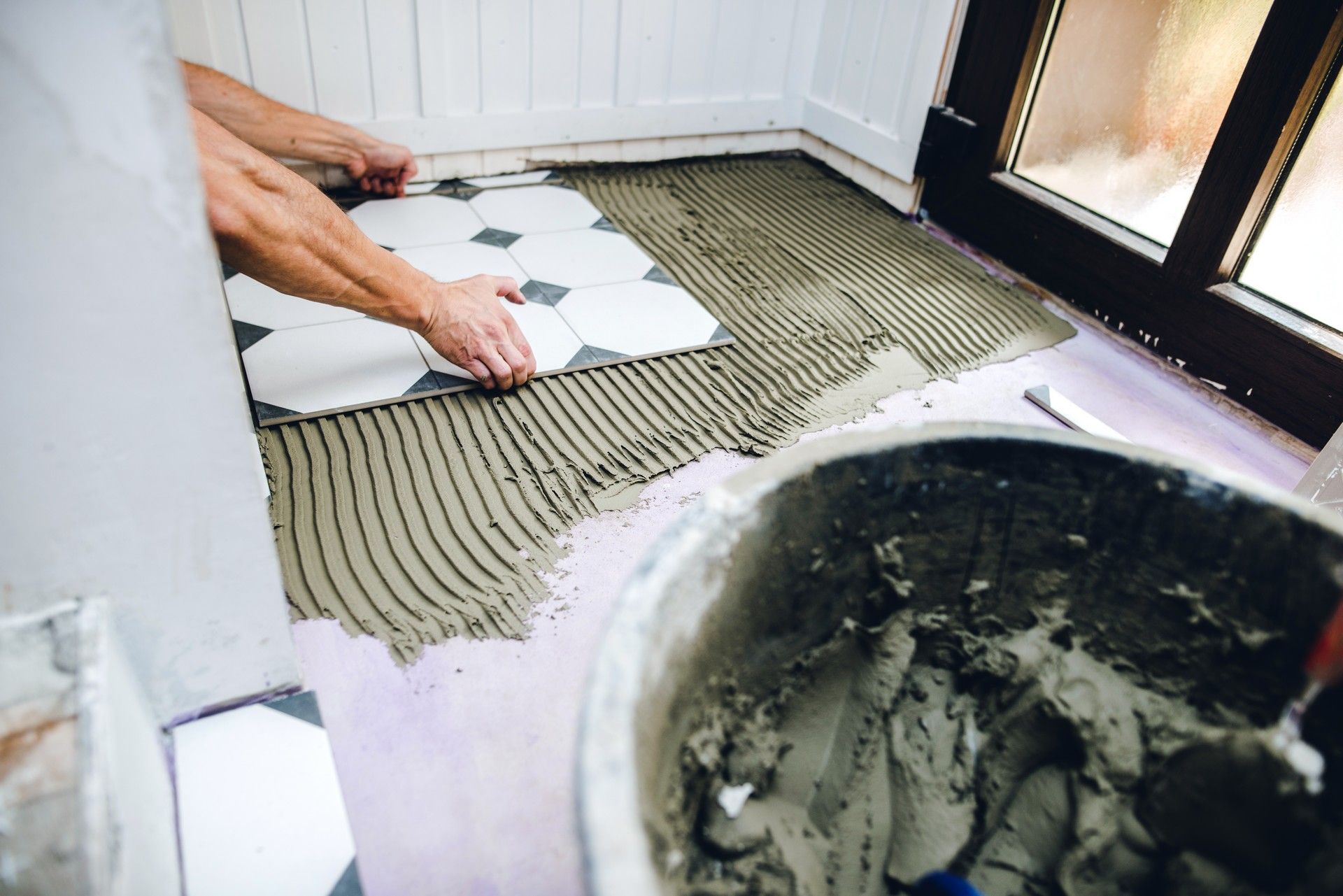 Un uomo sta posando le piastrelle sul pavimento del bagno.