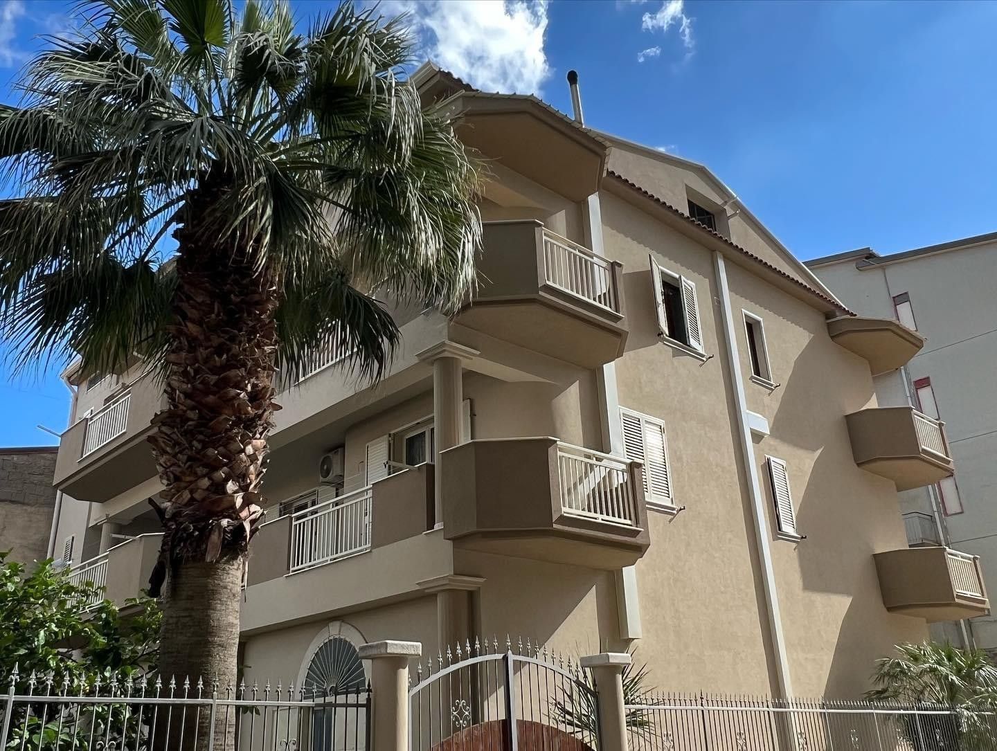 Un grande edificio con una palma di fronte