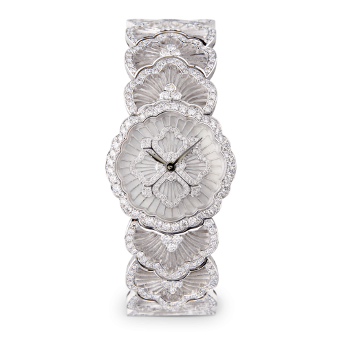 Un orologio in oro bianco con un fiore sul quadrante è su uno sfondo bianco.