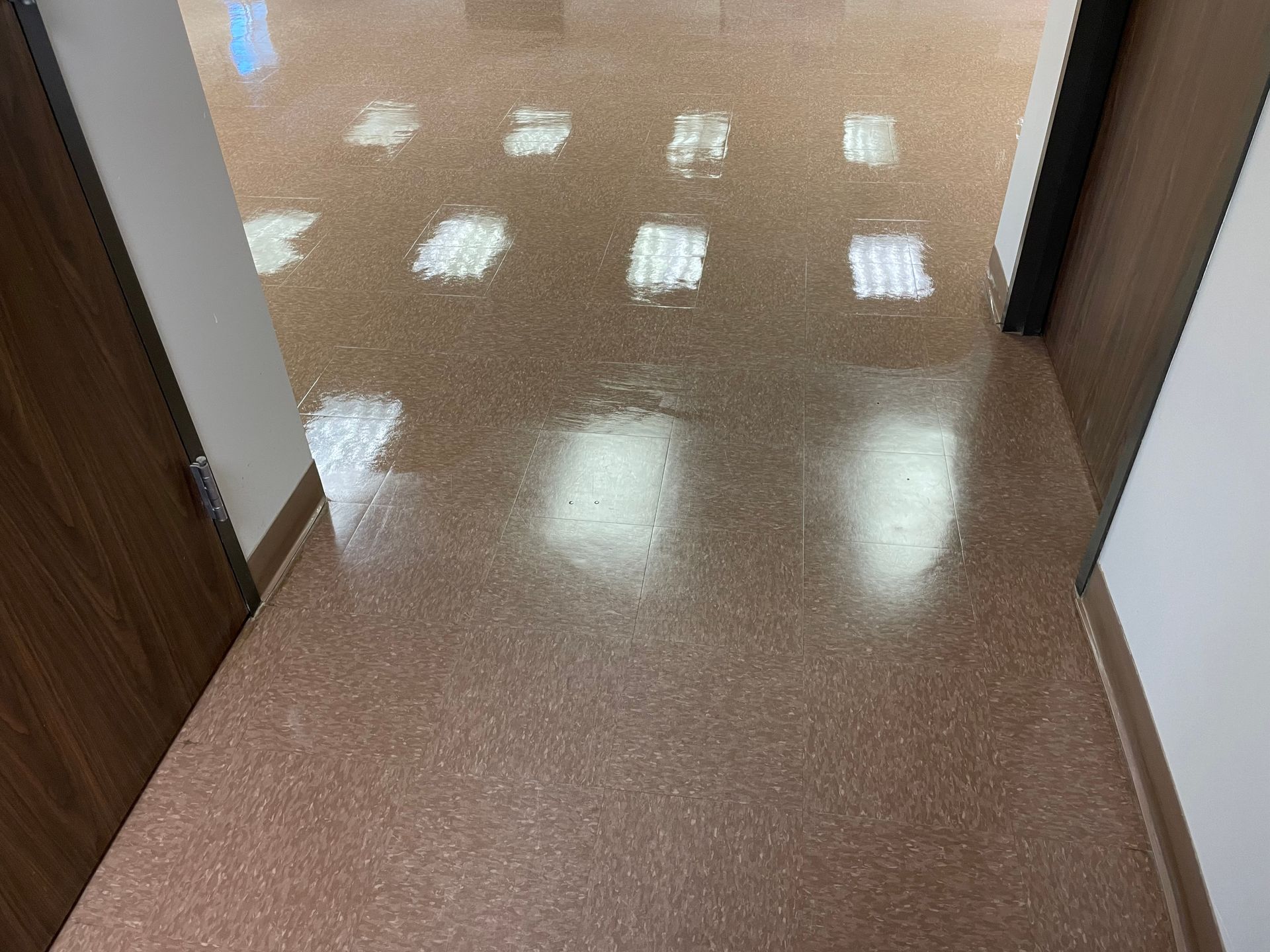 A hallway with a shiny floor and a door.