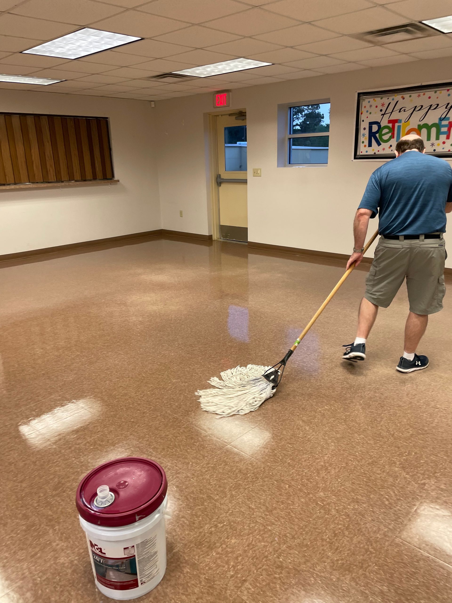 A man is mopping the floor of a room with a mop.