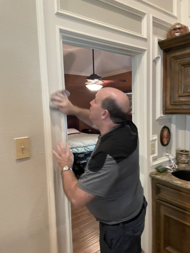 A man is cleaning a door in a kitchen.