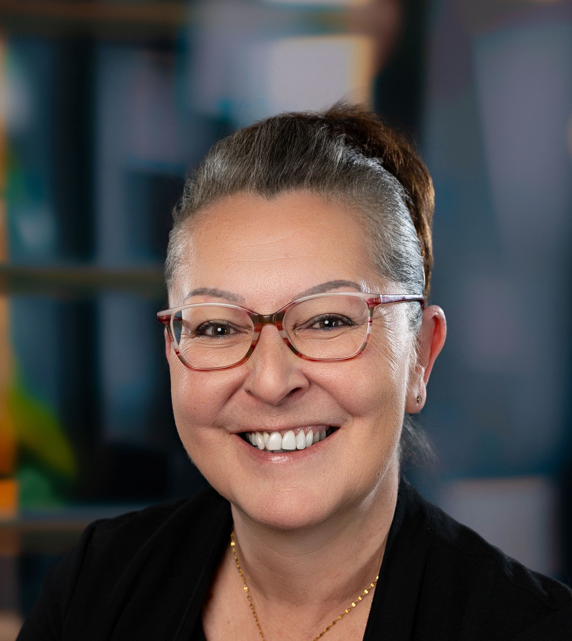 Une femme portant des lunettes et une veste blanche sourit à la caméra