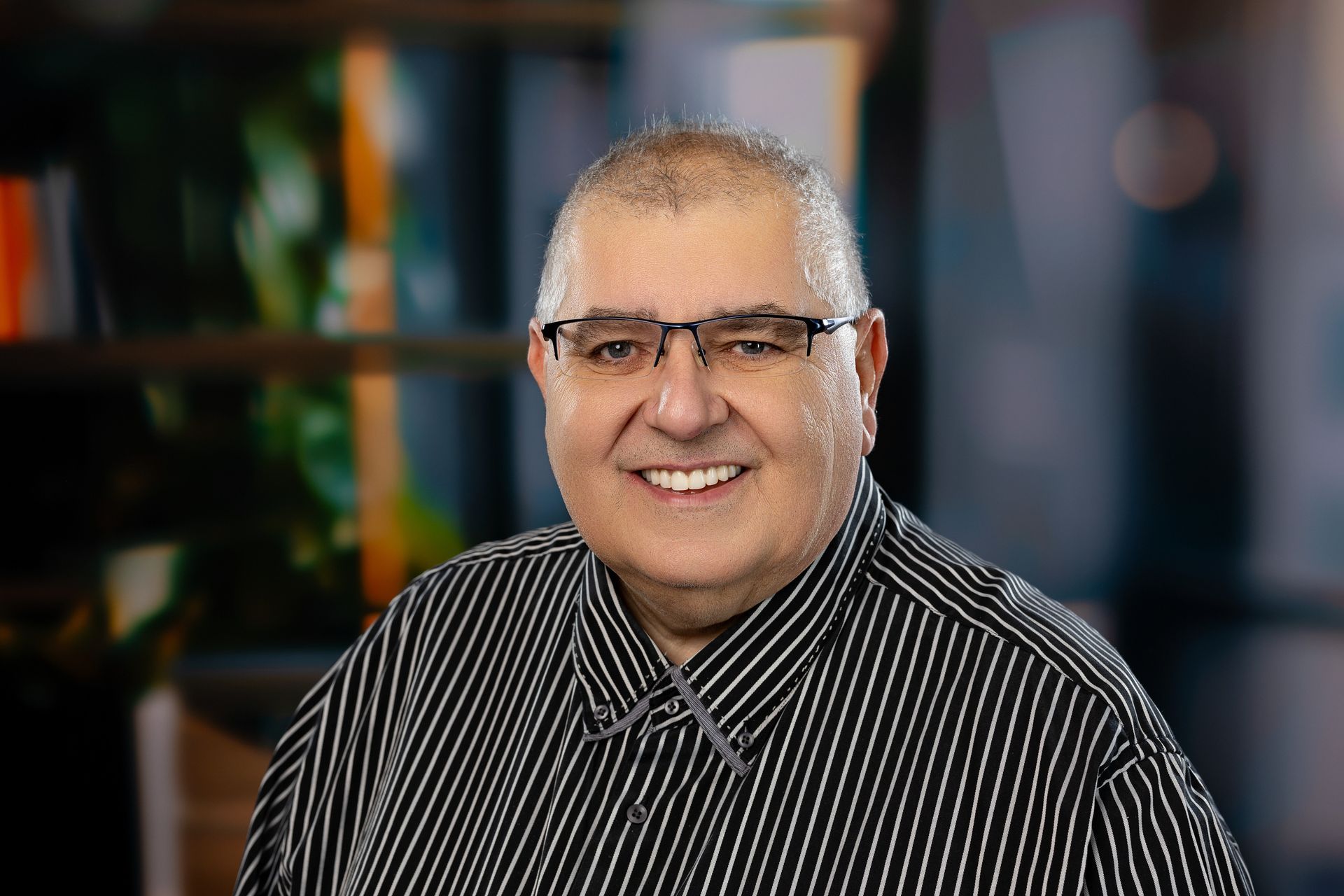 Un homme portant des lunettes et une chemise bleue avec un ruban noir autour du cou