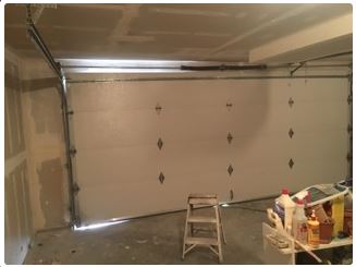 Garage interior with a partially open white door, a stepladder, and construction materials.