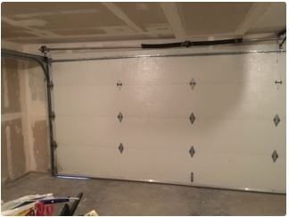 White closed garage door inside unfinished room.