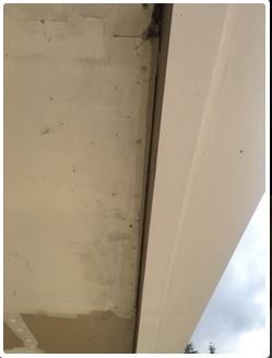 Close-up of a white, angled ceiling and a white trim. Part of the sky is visible on the right.