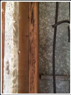 Wooden door frame and textured metal siding, with a dark metal bar on the right.