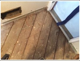 Wooden floor, vent, and doorway with a blue strap. Boards appear old and worn.