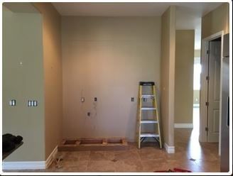 Empty kitchen wall with ladder and exposed wiring, ready for appliance installation.