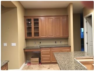 Kitchen with light brown cabinets, granite countertops, and tan walls.