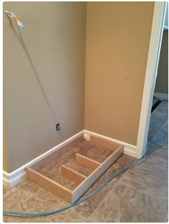 Wooden frame installed in a corner, on tiled floor. Beige walls, white trim, and blue wire present.
