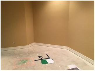Empty room with tan walls and white trim. Concrete floor with debris; sample cards on floor.