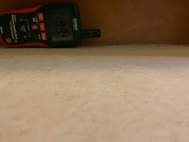 A moisture meter displays 9.7% moisture on a wooden surface.