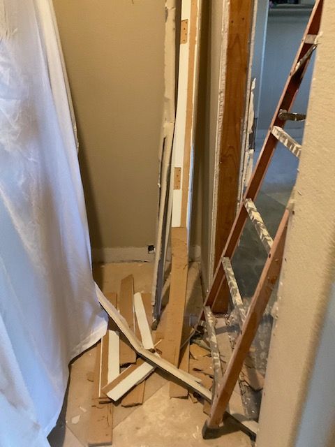 Construction materials cluttering a narrow hallway: doors, wood pieces, and a ladder.