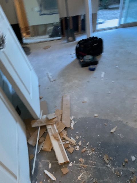 Demolished wood pieces on a concrete floor near a white door in a construction site.