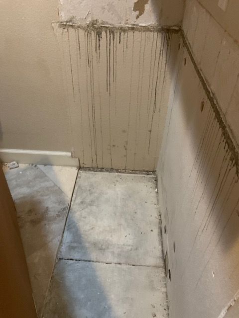 Muddy walls and floor in a small corner space, likely undergoing construction or repair.
