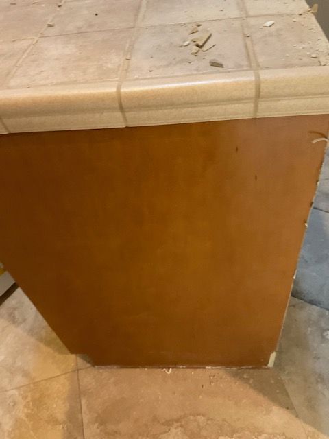 Brown cabinet with tiled countertop, set on tile floor.