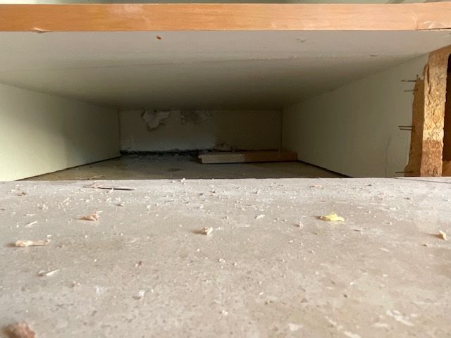 A long, rectangular, empty space; beige walls and floor, wood structure to the right.